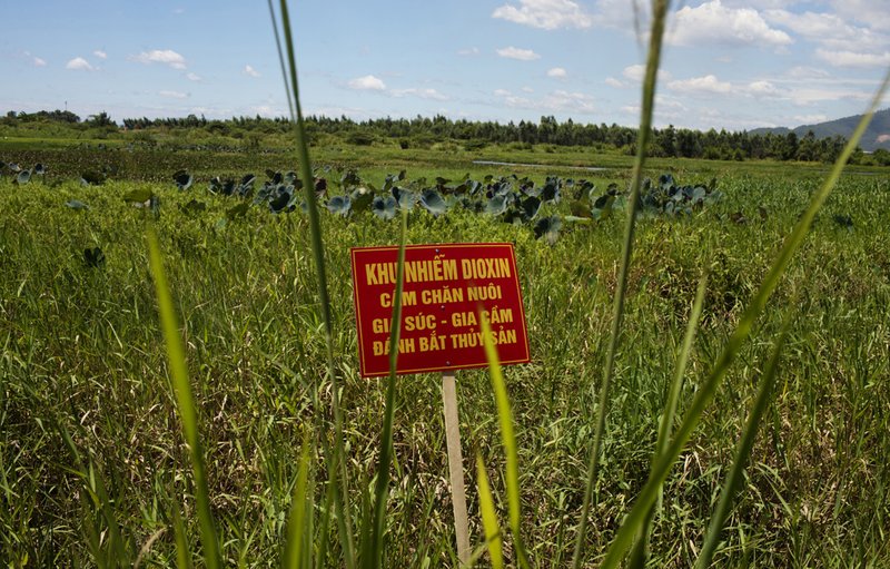 In this Aug. 9, 2012, file photo, a warning sign stands in a field contaminated with dioxin near Danang airport, during a ceremony marking the start of a project to clean up dioxin left over from the Vietnam War, at a former U.S. military base in Danang, Vietnam. (AP Photo/Maika Elan, File)