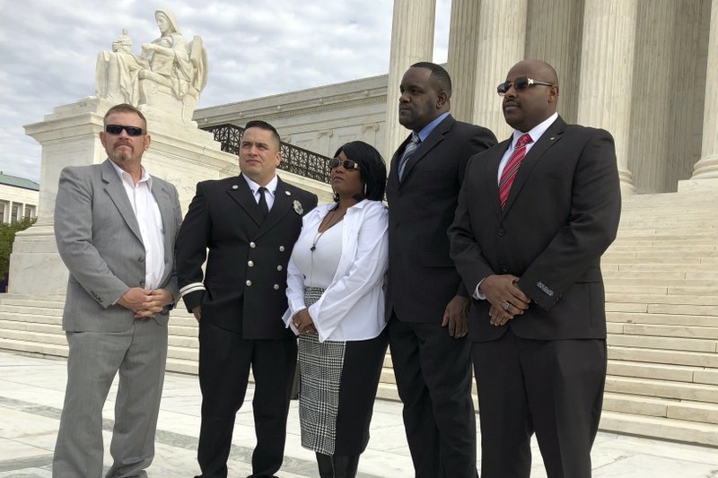 A group of victims of the USS Cole bombing, from left Rick Harrison and David Morales, who were aboard the USS Cole when it was bombed, and Lorrie Triplett, Jamal Gunn and David Francis, who all lost family members in the bombing. pose outside the Supreme Court in Washington, Wednesday, Nov. 7, 2018, following arguments in a case that stemmed from the bombing. (AP Photo/Jessica Gresko)