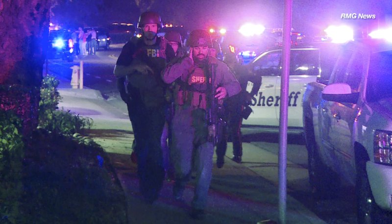 In this image taken from video police officers and FBI agents run at the scene of a shooting, early Thursday morning, Nov. 8, 2018, in Thousand Oaks, Calif. A hooded gunman dressed entirely in black opened fire on a crowd at a country dance bar holding a weekly "college night" in Southern California, killing multiple people and sending hundreds fleeing including some who used barstools to break windows and escape, authorities said Thursday. The gunman was later found dead at the scene. (RMG News via AP)

