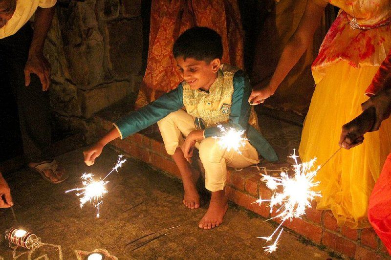 Karthik Thotakura holds out one of the sparklers lighting the night at a Diwali gathering in Little Rock on Tuesday. 