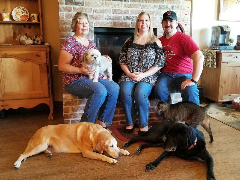 Better together: Sherry Lopatic (left), pictured with her daughter and son-in-law, Rachel and Michael Tidwell, three of their five dogs — Kit, the yellow Lab; Sadie, the black Lab; Grace, the Shih Tzu — and Harley, the cat.