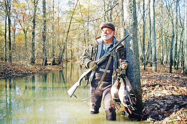 In this file photo Sammie Faulk of Lake Charles, La., takes in a peaceful moment after a successful hunt in the flooded green timber of an east Arkansas wildlife management area. These bottomland areas managed by the Arkansas Game and Fish Commission provide unexcelled hunting for mallards and other ducks.