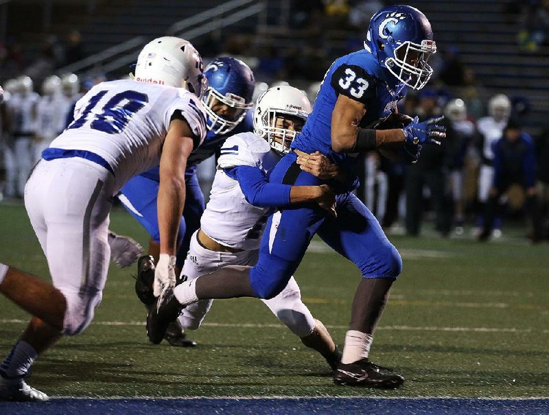 Conway running back Cary McClain (33) drags Rogers defensive back Christian Francisco (1) with him into the end zone for a touchdown during the second quarter Friday at John McConnell Stadium in Conway. McClain rushed for three touchdowns as the Wampus Cats won 49-7 and advance to play at Bentonville West in next week’s Class 7A quarterfinals. 