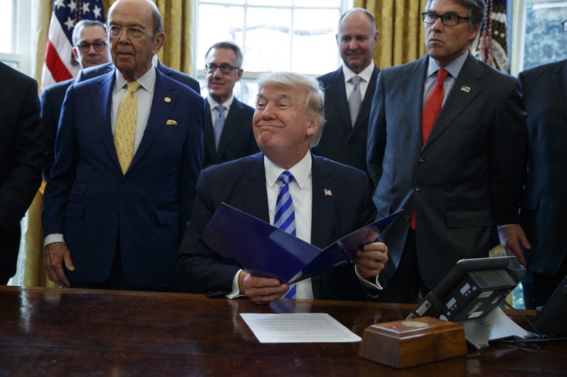 In this March 24, 2017 file photo, President Donald Trump, flanked by Commerce Secretary Wilbur Ross, left, and Energy Secretary Rick Perry, is seen in the Oval Office of the White House in Washington, during the announcing of the approval of a permit to build the Keystone XL pipeline, clearing the way for the $8 billion project. (AP Photo/Evan Vucci, File)