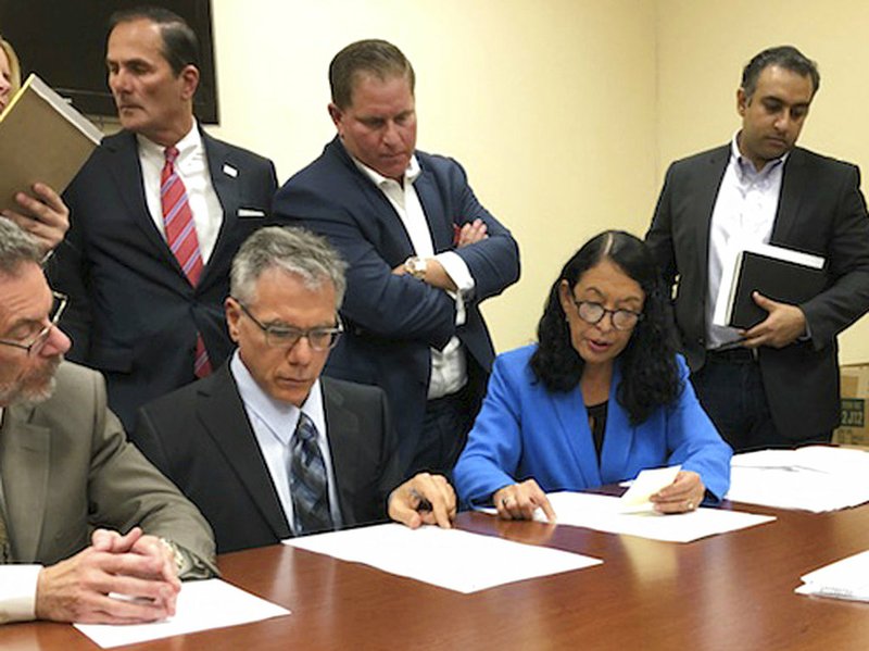 Susan Bucher, second right, Palm Beach County Supervisor of Elections and Judge August Bonavita, seated at center left, look at provisional ballots in Riviera Beach, Fla., Friday, Nov. 9, 2018. A possible recount looms in a tight Florida gubernatorial, U.S. Senate and agriculture commission race. (AP Photo/Josh Repogle)