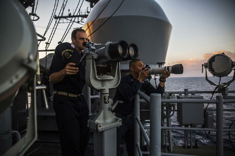 Sailors from the USS Chancellor’s “Snoopie” data collection team observe and photograph a Chinese frigate that was following them in the South China Sea during a patrol in March 2016.