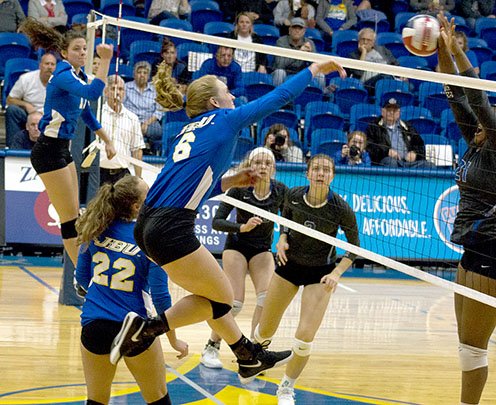 Photo courtesy of JBU Sports Information John Brown junior Kinzee Mayo goes up for a hit, while Southwestern Christian (Okla.) blocker Jamesha Redd goes up for a block during Tuesday's game at Bill George Arena. SCU swept the match to end JBU's season.