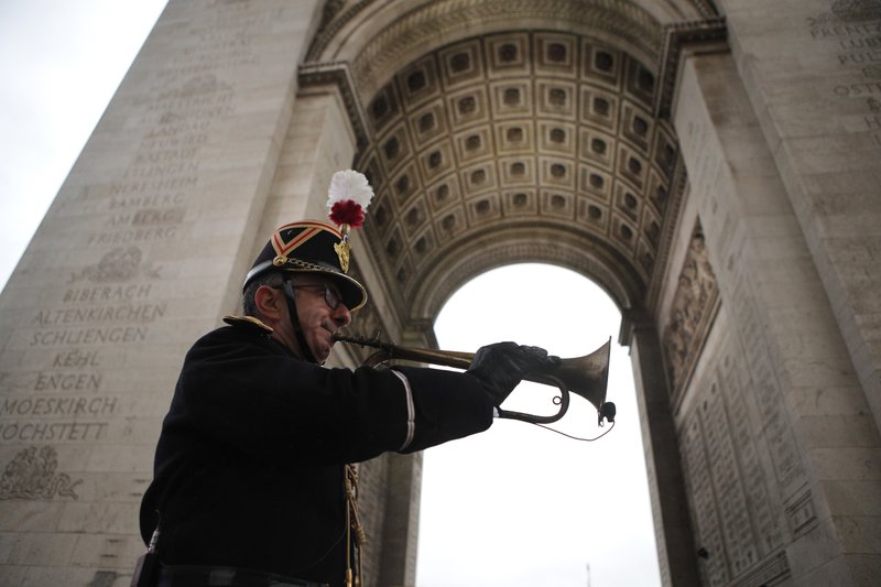 A military officer plays the original Armistice bugle from 1918 under the Arc de Triomphe Sunday, Nov. 11, 2018 in Paris. (AP Photo/Francois Mori, Pool)