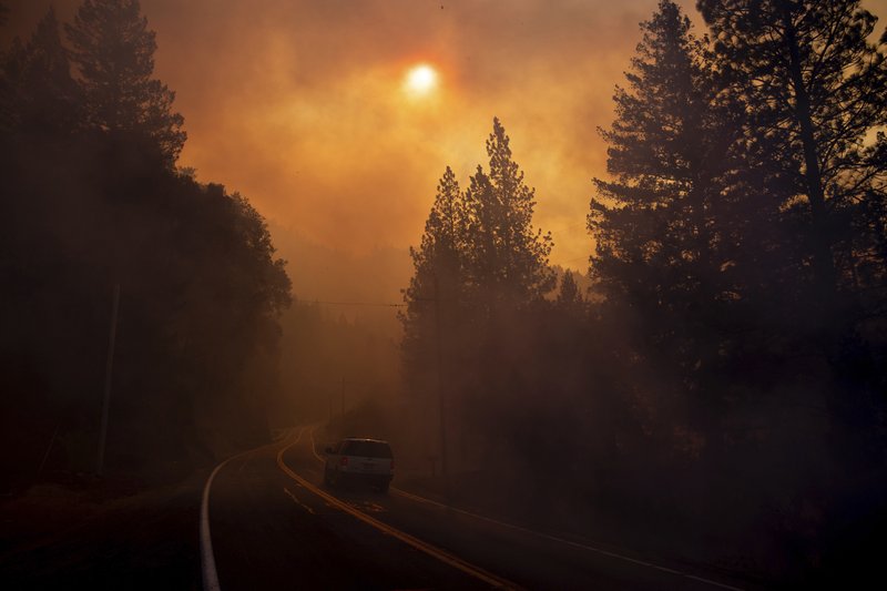 A vehicle drives through smoke from a wildfire near Pulga, Calif., Sunday, Nov. 11, 2018. (AP Photo/Noah Berger)