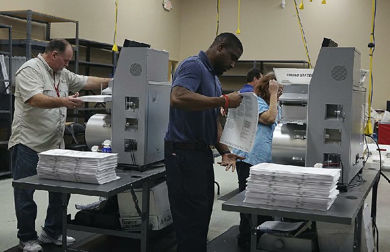 Election workers place ballots into electronic counting machines Sunday at the Broward Supervisor of Elections office in Lauderhill, Fla. 