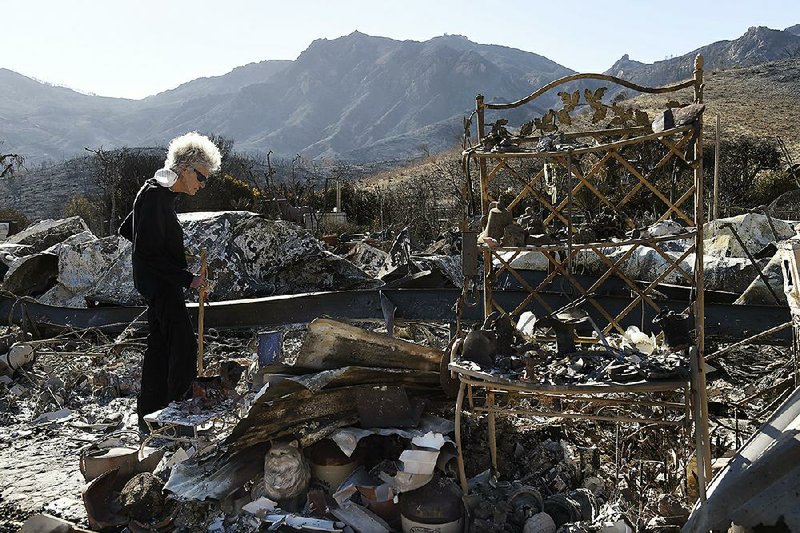 Marsha Maus, a longtime resident of the Seminole Springs Mo- bile Home Park in Agoura Hills, Calif., looks through her charred belongings Sunday after wildfires destroyed her neighborhood. 