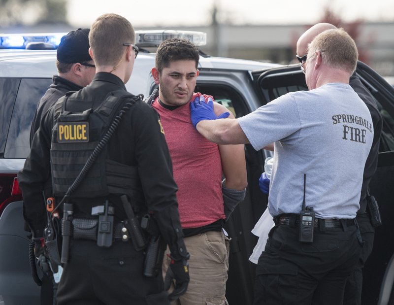 NWA Democrat-Gazette/BEN GOFF @NWABENGOFF
Medics from the Springdale Fire Department treat a man wearing handcuffs Sunday, Nov. 11, 2018, at the scene of a shooting on Don Tyson Parkway near the intersection with South Thompson Street in Springdale. 