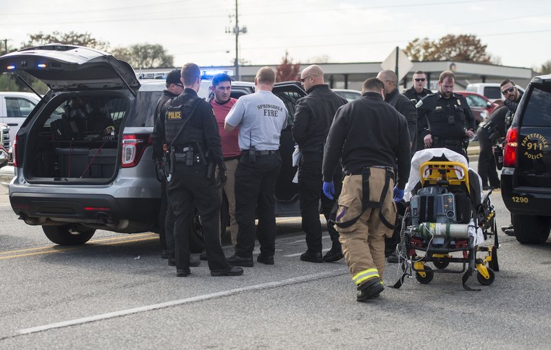 NWA Democrat-Gazette/BEN GOFF
Medics from the Springdale Fire Department treat a man wearing handcuffs Sunday, Nov. 11, 2018, at the scene of a shooting on Don Tyson Parkway near the intersection with South Thompson Street in Springdale.
