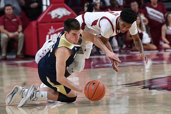 Guards Isaiah Joe of Arkansas (top) and Joe Mooney of UC Davis go after a loose ball during a game Monday, Nov. 12, 2018, in Fayetteville. 