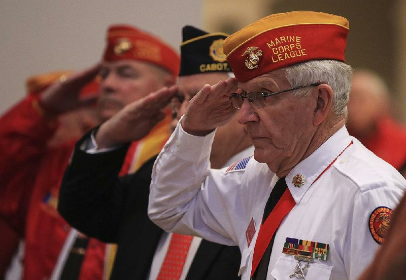 Veterans including Paul Garrett (right) with the Marine Corps League Sidney S. McMath/Razorback Detachment salute Monday as the colors are posted during a Veterans Day ceremony in Little Rock.