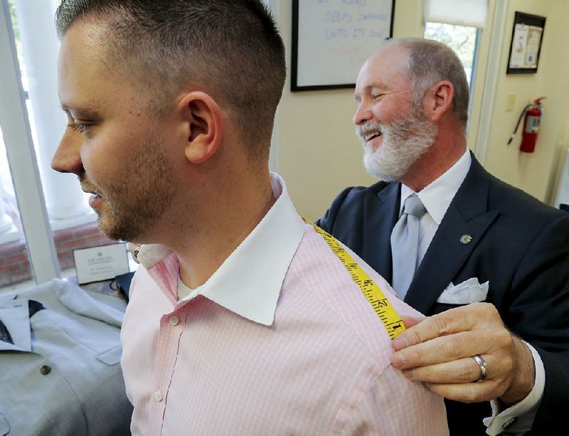 Custom clothier Paul Rainwater (right) measures the shoulders of client Dr. Grant Dennis. 