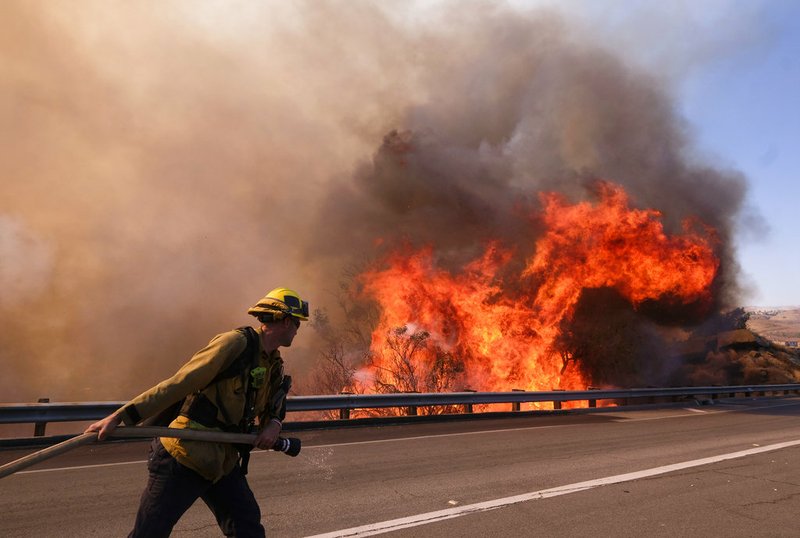 A firefighter battles a fire along the Ronald Reagan (118) Freeway in Simi Valley, Calif., Monday, Nov. 12, 2018. (AP Photo/Ringo H.W. Chiu)