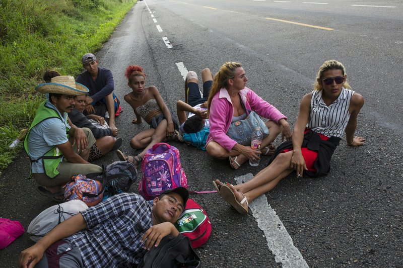 In this Nov. 2, 2018 photo, members of the LGBTQ community who are traveling with the Central American migrants caravan hoping to reach the U.S. border, wait on the side of the road for a ride to Donaji, Mexico. Fearful of being attacked violently or sexually assaulted, they've stuck by each other's side 24 hours a day, walking and sleeping in a group. (AP Photo/Rodrigo Abd)