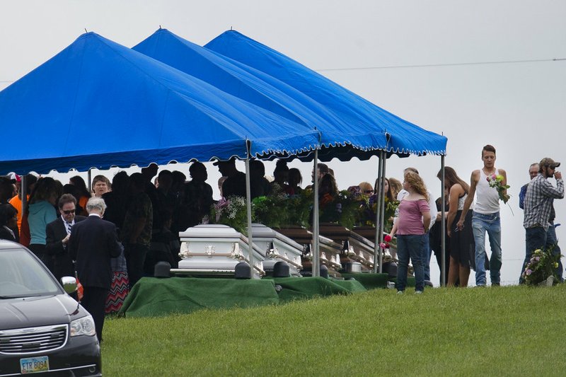 FILE -- In this May 3, 2016, file photo, mourners gather around caskets for six of the eight members of the Rhoden family found shot April 22, 2016, at four properties near Piketon, Ohio, during funeral services at Scioto Burial Park in McDermott, Ohio. Authorities say Tuesday, Nov. 13, 2018, that a family of four has been arrested in in the slayings of eight members of one family in rural Ohio two years ago. (AP Photo/John Minchillo, File)