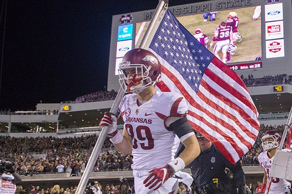 Arkansas tight end Grayson Gunter carries the American flag onto the field prior to a game against Mississippi State on Saturday, Nov. 19, 2016, in Starkville, Miss. 