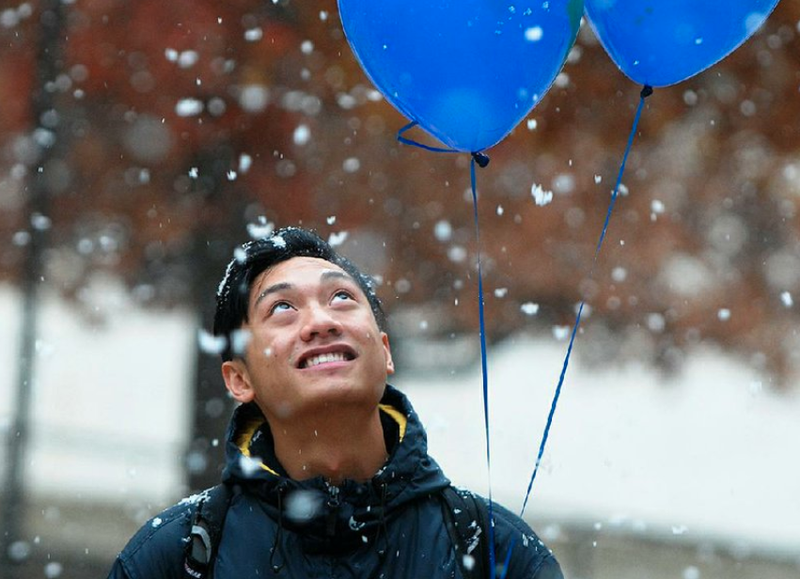 Vince Sayarath, a senior at the University of Arkansas, Fayetteville, watches snowflakes Monday as he walks across campus. Parts of Northwest Arkansas received a mix of rain, snow and sleet. - Photo by David Gottschalk
