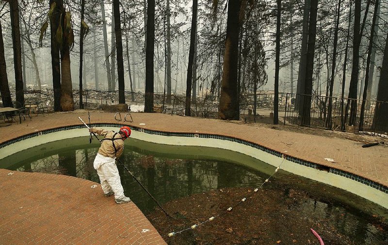A search-and-rescue team member checks a swimming pool for remains Tuesday at a mobile home park in fire-ravaged Paradise, Calif., where a number of people remain missing. 