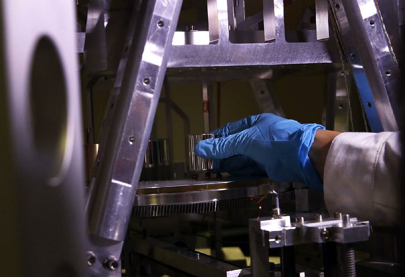 Dr. Hao Fang of the International Bureau of Weights and Measures in Sevres, France, sets up the so-called Grand K, the golf ballsized metal cylinder used as the worldwide standard for the mass of a kilogram. The physical prototype is expected to be replaced Friday by a scientific formula to define the exact weight of a kilo. story.lead_photo.caption