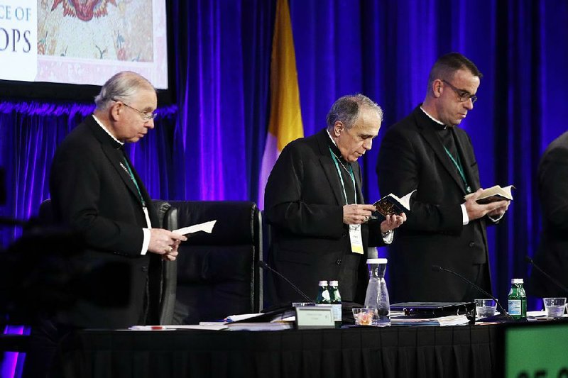 Archbishop Jose Gomez (from left) of Los Angeles, Cardinal Daniel DiNardo of the Galveston-Houston Diocese, and the Rev. J. Brian Bransfield take part in a morning prayer Tuesday at the U.S. Conference of Catholics Bishops meeting in Baltimore. 
