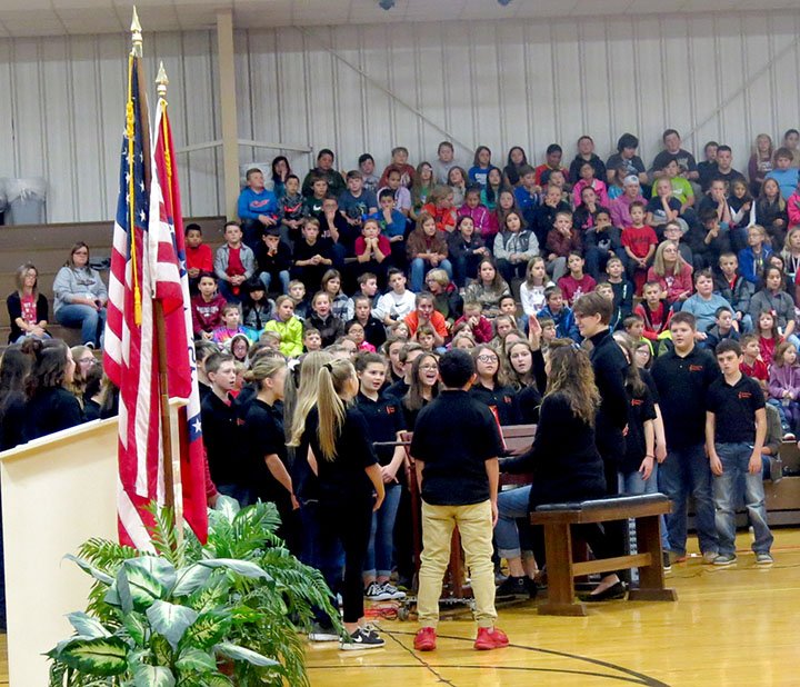 Westside Eagle Observer/SUSAN HOLLAND Members of the Gravette Middle School choir sing &quot;Salute to the Armed Forces,&quot; a medley of songs honoring various branches of the military, at an assembly Friday morning, Nov. 9, in the competition gym. The patriotic program honoring veterans also featured a video salute prepared by the Builders Club.