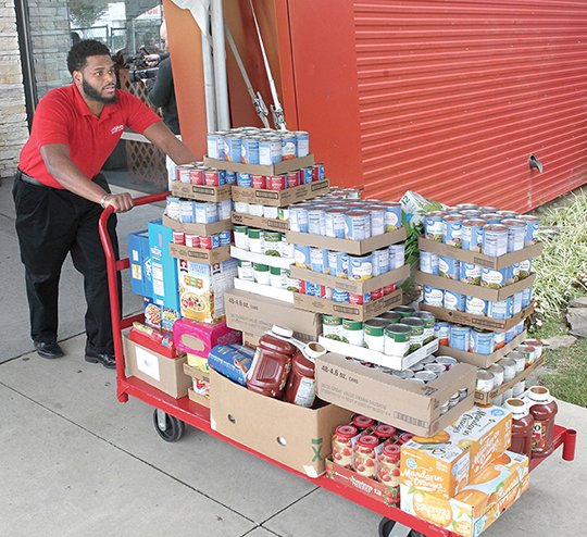 Oaklawn Racing &amp; Gaminf employee Alex Richardson pushes one of loads of non-perishable food items toward a delievery truck Tuesday, November 13, 2018. The food was collected last week during Oaklawn's annual Yes We Can Food Drive and will be was being deleiverd to First United Methodist Community Food Pantry, Jackson House and Ali&#x2019;s A.C.E. Closet. This is the seventh year that Oaklawn has held the food drive. (The Sentinel-Record/Richard Rasmussen)
