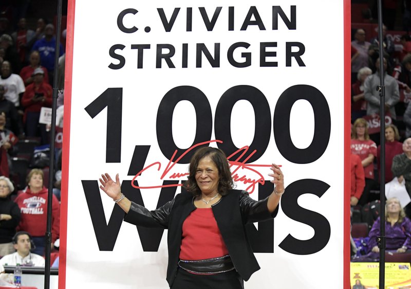 Rutgers head coach C. Vivian Stringer poses in front of a banner that will hang from the rafters after Rutgers defeated Central Connecticut for Stringer's 1,000th career NCAA college basketball game win, Tuesday, Nov. 13, 2018, in Piscataway, N.J. (AP Photo/Bill Kostroun)