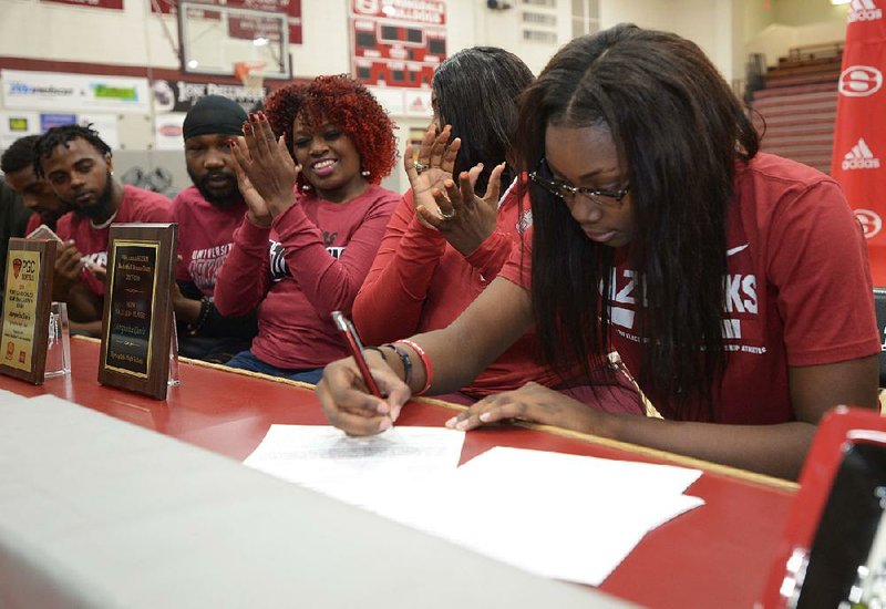 Springdale guard Marquesha Davis signs a letter of intent to play basketball at Arkansas on Wednesday as friends and family look on.