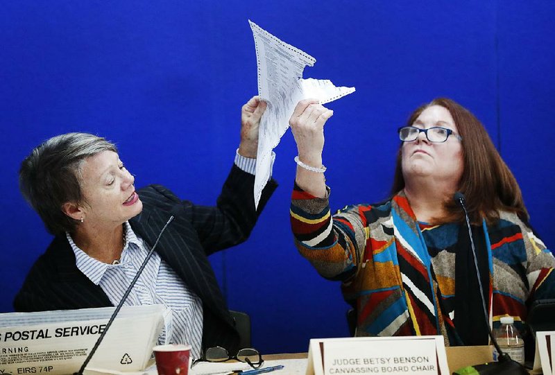 Canvassing board chairman Judge Betsy Benson (left) and board member Judge Deborah Carpenter-Toye show political lawyers Wednesday one of the ballots that was damaged during the recount at the Broward County supervisor of elections office in Lauderhill, Fla. 