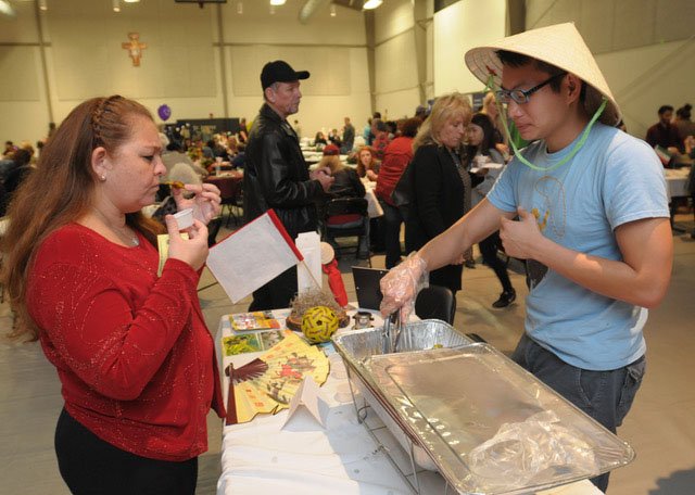 File Photo/ANDY SHUPE Luz Morlet of Fayetteville (left) tastes a sample of banh xeo, a savory dish from Vietnam, with some help from Tu Le, a University of Arkansas student from Vietnam, during a previous M&N Augustine Foundation International Festival.