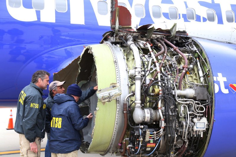 In this April 17, 2018, file photo National Transportation Safety Board investigators examine damage to the engine of the Southwest Airlines plane that made an emergency landing at Philadelphia International Airport in Philadelphia. In new accounts released Wednesday, Nov. 14, into the April accident, the flight attendants described being unable to bring the woman back in the plane until two male passengers stepped in to help.  (NTSB via AP)