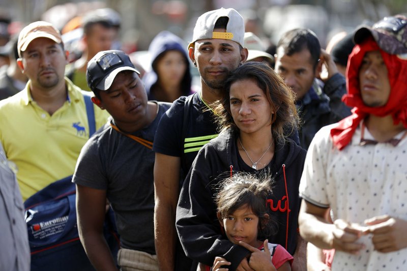 Marvin Ochoa, center, of Honduras, waits in line for a meal behind his wife Diana Marylin Ochoa after they arrived with a Central America migrant caravan to Tijuana, Mexico, Thursday, Nov. 15, 2018. Members of the migrant caravan started to meet some local resistance as they continued to arrive by the hundreds in the Mexican border city of Tijuana, where a group of residents clashed with migrants camped out by the U.S. border fence. (AP Photo/Gregory Bull)