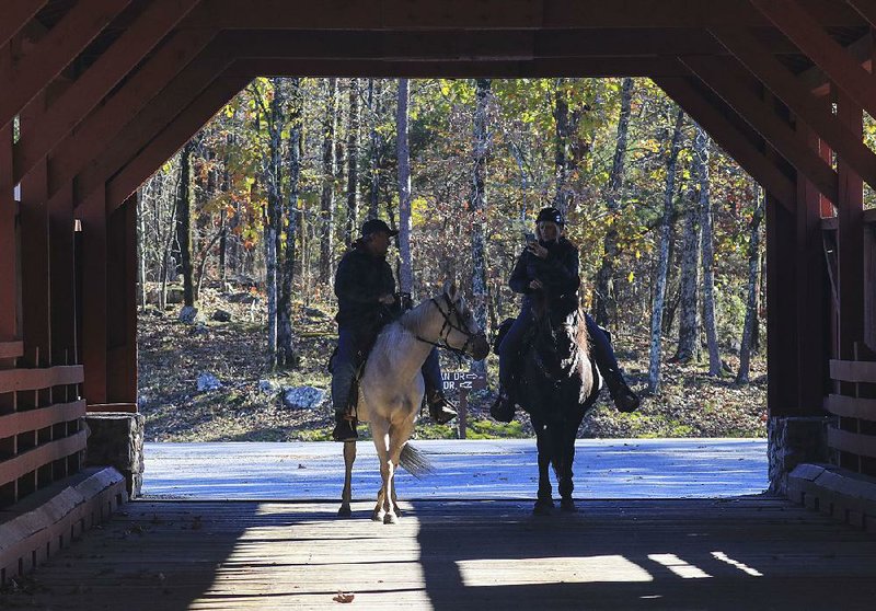 FILE — Craig Batek (left) on Pistol and Kim Batek on Polly ride across the covered bridge on Nov. 15 in North Little Rock's Burns Park. 