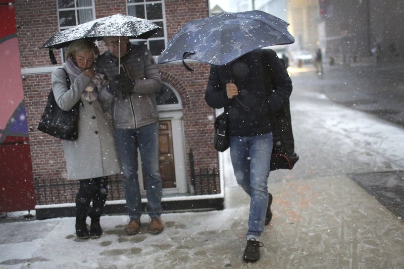 A couple take shelter under an umbrella from snowfall in front of a mural while another man walks past them in lower Manhattan on Thursday, Nov. 15, 2018, in New York. (AP Photo/Wong Maye-E)