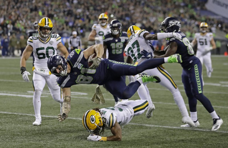 Seattle Seahawks tight end Nick Vannett (81) gets horizontal above Green Bay Packers cornerback Tramon Williams, lower-center, as Vannett carries the ball just short of the goal line against the Green Bay Packers during the first half of an NFL football game, Thursday, Nov. 15, 2018, in Seattle. (AP Photo/Stephen Brashear)