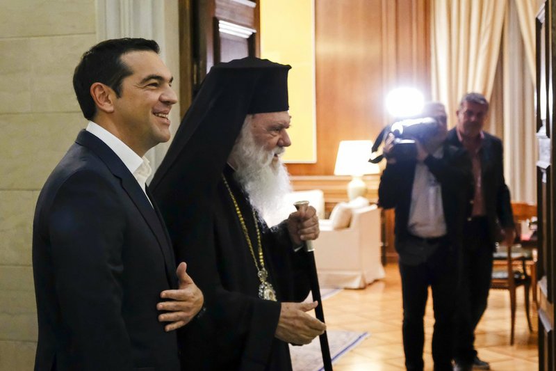 In this photo released by Greek Prime Minister's office, Greece's Prime Minister Alexis Tsipras, left, and Church head Archbishop Hieronymos arrive for their meeting at Maximos Mansion in Athens on Tuesday, Nov. 6, 2018. Greece's left-led government and the country's powerful Church say they have struck a tentative deal to end decades of discord over the exploitation of large tracts of real estate both claim as their own. (Andrea Bonetti/Greek Prime Minister's Office via AP)