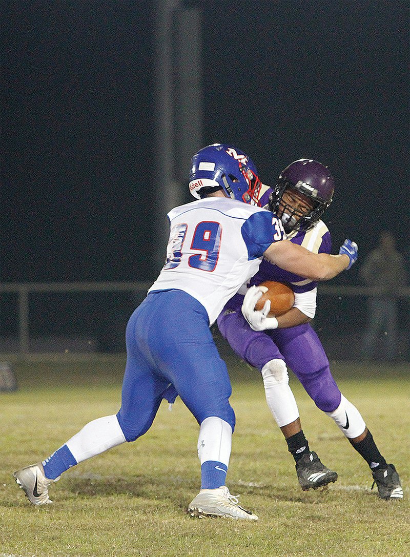 Terrance Armstard/News-Times Junction City running back Jakiron Cook tries to break from the grasp of Mountainburg's  Malachi West (39) during their contest in the second round of the 2A playoffs Friday night in Junction City. The Dragons advanced to the quarterfinals with a 50-14 victory over Mountainburg.