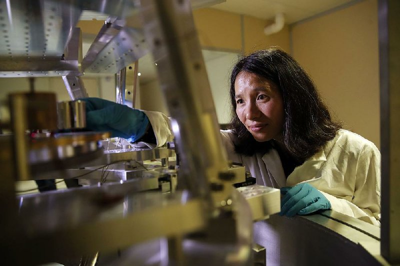 Dr. Hao Fang of the International Bureau of Weights and Measures, in Sevres, France, works in October with the Grand K, the metal cylinder used to measure the mass of a kilogram, which soon will be replaced by a scientific formula. 