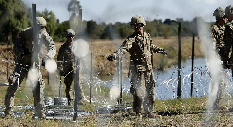 U.S. troops install concertina wire Friday along the Rio Grande near the Juarez-Lincoln Bridge at the U.S.-Mexico border in Laredo, Texas. 
