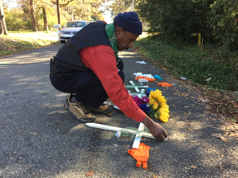 Earnest Franklin, a minister with Arkansas Stop the Violence, places crosses at the scene in Little Rock where three people were fatally shot Friday night, on the 4400 block of West 14th Street.