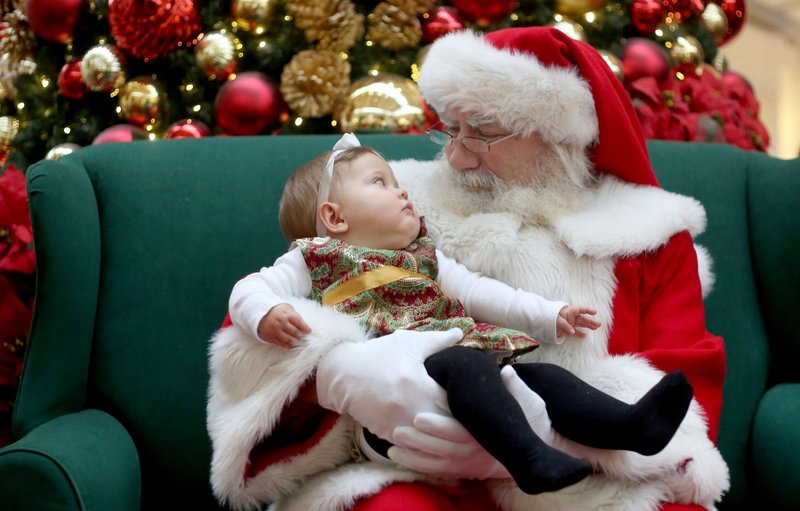 File Photo/DAVID GOTTSCHALK Santa Claus and Alexa Graham make eye contact before a formal portrait together last Christmas at the Northwest Arkansas Mall in Fayetteville.