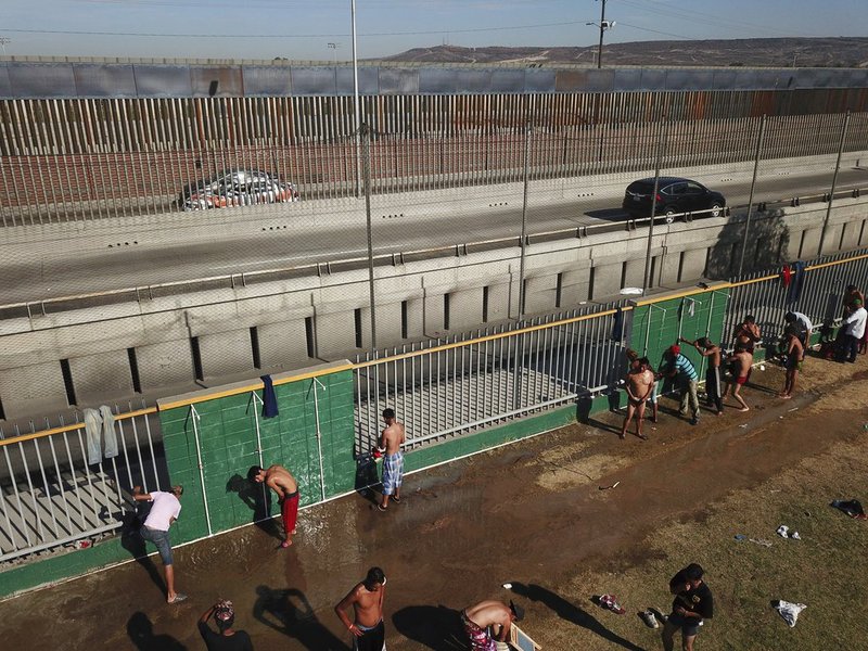 Central American migrants bathe at a temporary shelter, near barriers that separate Mexico and the United States, at a temporary shelter in Tijuana, Mexico, early Saturday morning, Nov. 17, 2018. Many of the nearly 3,000 migrants have reached the border with California. The mayor has called the migrants' arrival an "avalanche" that the city is ill-prepared to handle. (AP Photo/Rodrigo Abd)