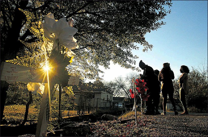 Family members of one of the victims visit a makeshift memorial Saturday where three people were killed and another injured on West 14th Street in Little Rock. The family members asked not to be identified. - Photo by Thomas Metthe
