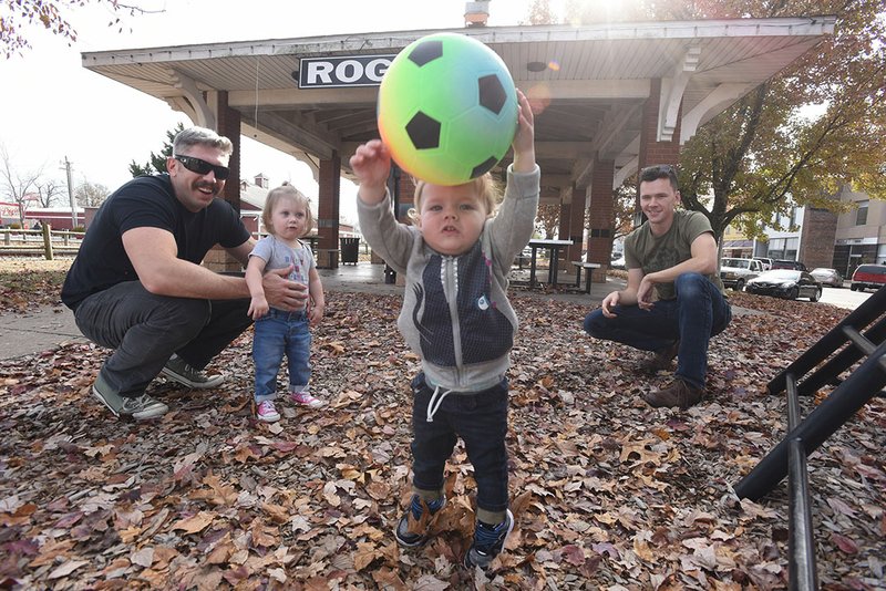 NWA Democrat-Gazette/FLIP PUTTHOFF Thompson Lockwood, 1, is the soccer star Saturday while playing at Frisco Park in Rogers with his dad, Lance Lockwood (right), Matt Burgess (left) and Zoe Burgess, 1. Frisco park is being redisigned and will be renamed Railyard Park.