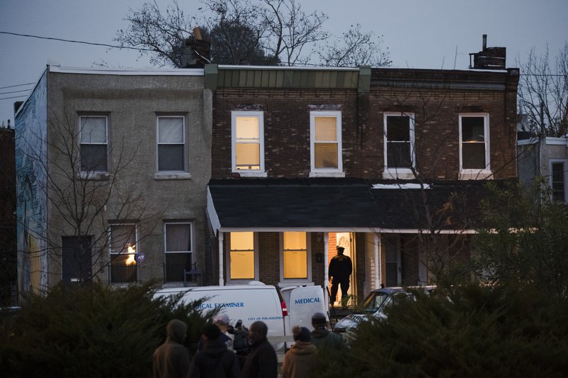 A police officer enters a row home to investigate a fatal shooting in Philadelphia, Monday, Nov. 19, 2018. Police say two men and two women have been found shot and killed in a basement in Philadelphia. (AP Photo/Matt Rourke)