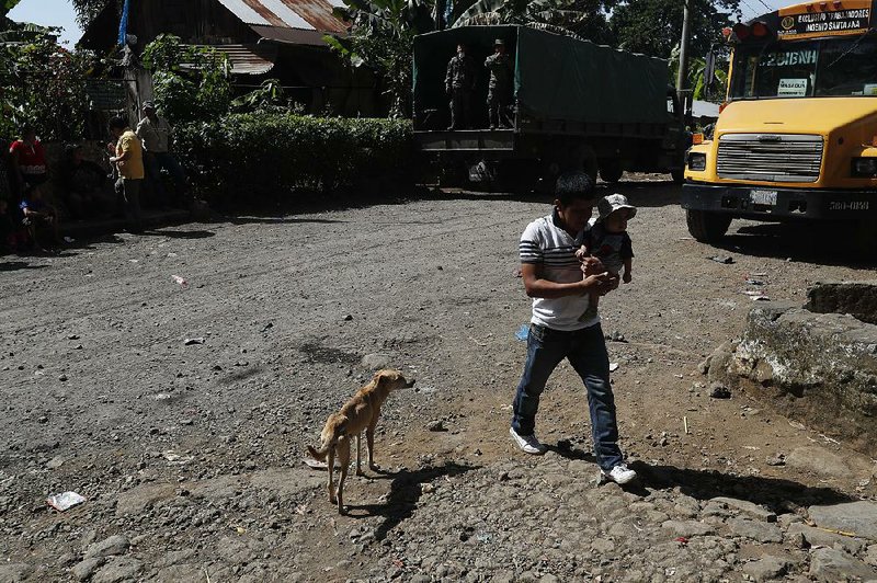 Residents prepare to evacuate their homes due to activity by the Volcan de Fuego, or Volcano of Fire, as soldiers observe Monday in San Andres Osuna, Guatemala. 